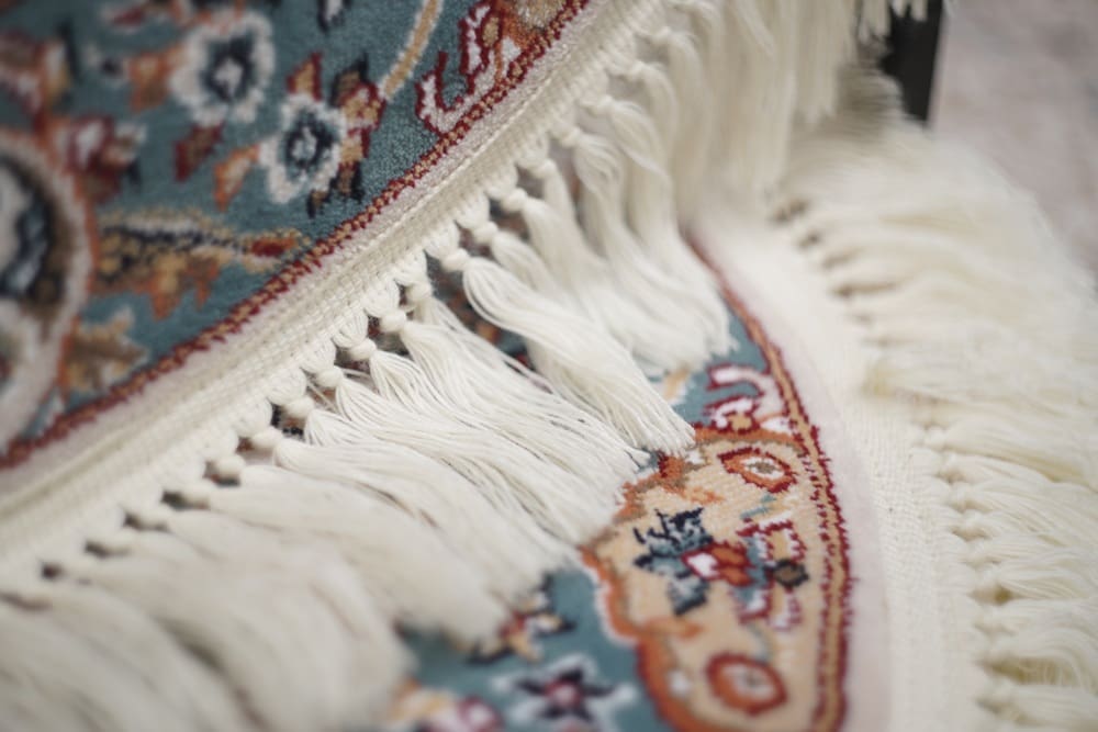 Close-up of a colorful patterned rug with intricate designs and white fringed edges, adding a touch of artistry to any space—similar to the detailed care found in alterations and tailoring Baldwinsville.